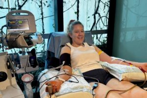 A woman smiling and relaxed in a donation chair during a PBSC stem cell collection procedure