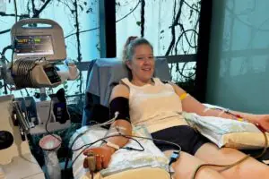 A woman smiling and relaxed in a donation chair during a PBSC stem cell collection procedure