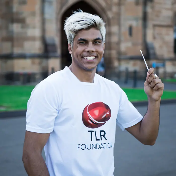 Amrit, a young Australian, holding up a cheek swab to show how easy it is to join the stem cell donor registry