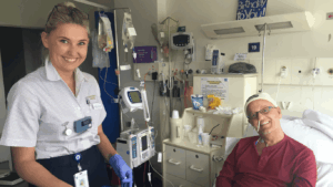 Trace Richey in a hospital bed sharing a moment with a nurse who cared for him through his blood cancer treatment.