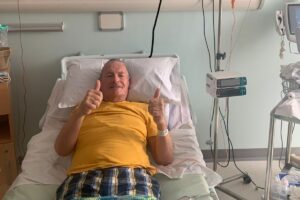 Man in hospital bed giving thumbs up during stem cell transplant