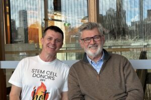 Neil and Dr Sam Milliken seated together smiling, city view behind